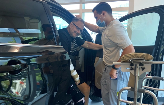 young man helping injured man into car