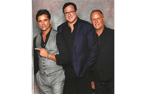 Three men in suits posing and smiling at the camera