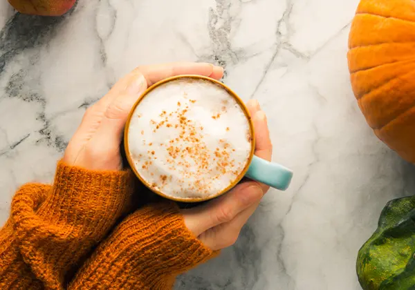 Close-up of hands holding a cup with a drink made from pumpkin