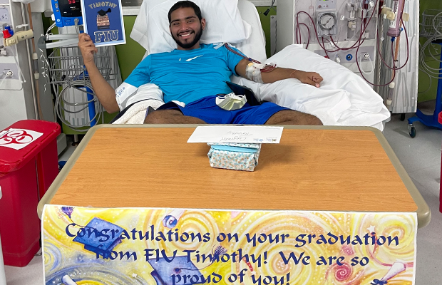 Young man on hospital stretcher smiling next to a sign
