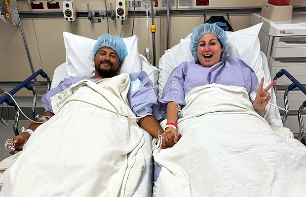 Man and woman lying on hospital stretcher while holding hands