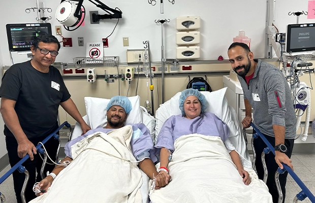Man and woman lying on hospital stretcher with two people around them