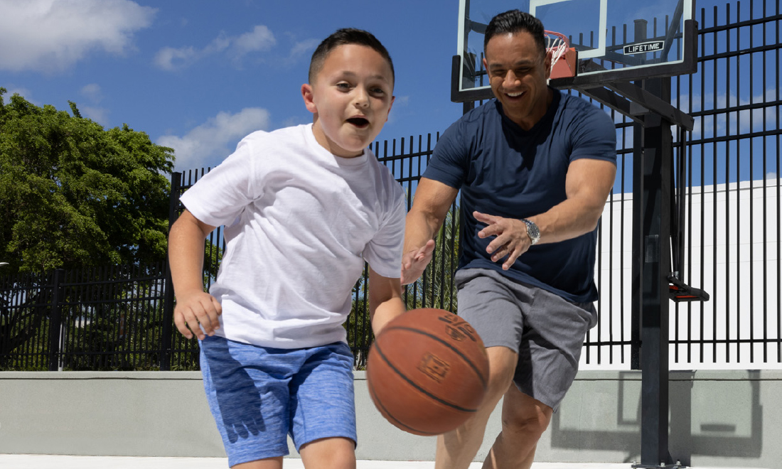 A man and his young son playing basketball outdoors