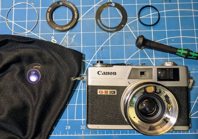 The front lens element out of the Canon QL17 for cleaning before removing secondary to access the shutter blades.