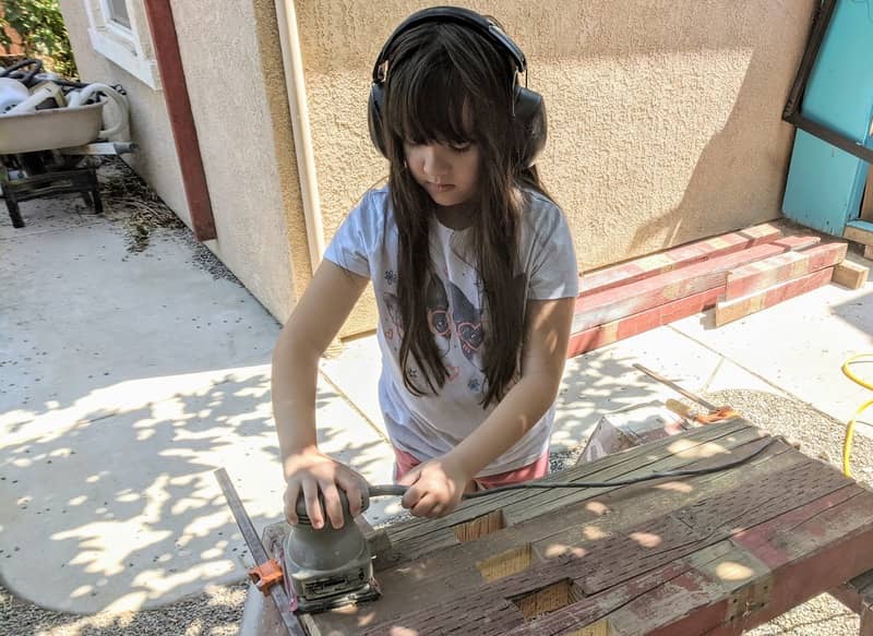 Evelyn cleaning up some of the reclaimed lumber with a sander.