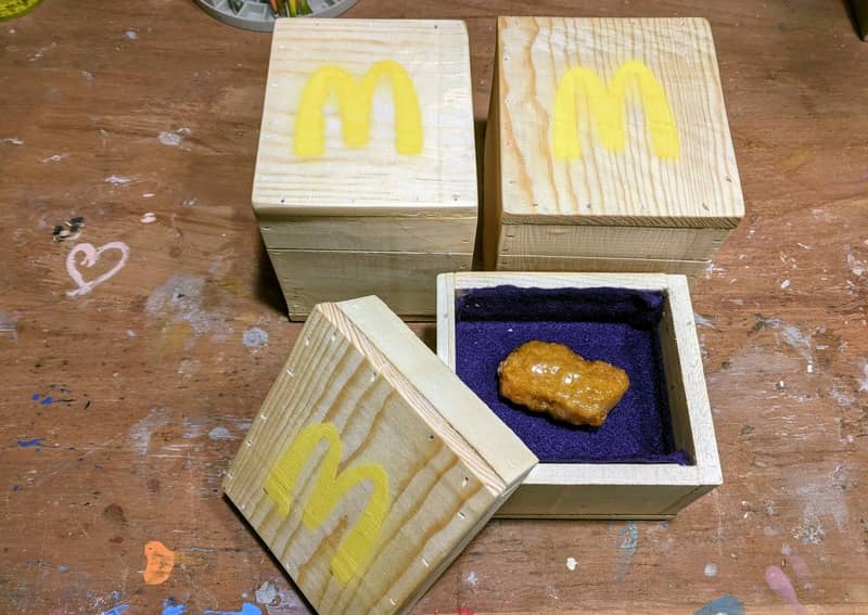 A lone resin-encased McNugget sits in Grimace-purple felted box ready for display.