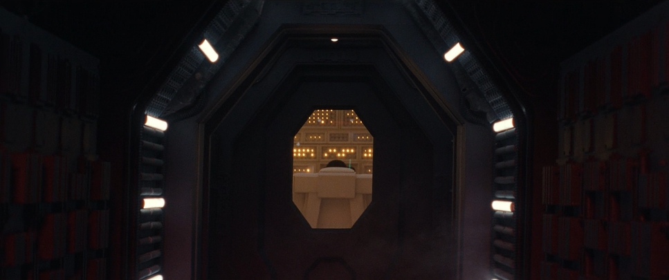 A dark architectural passage opens onto an illuminated machine chamber.
