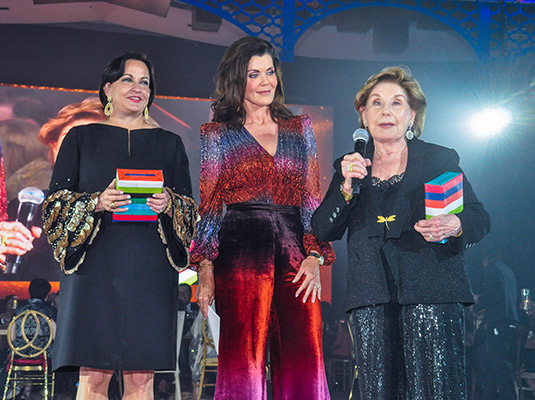 Three woman on a stage, one holds a microphone