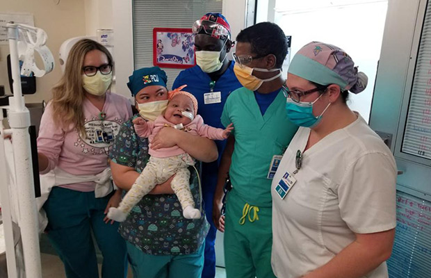 A baby being held and surrounded by medical professionals