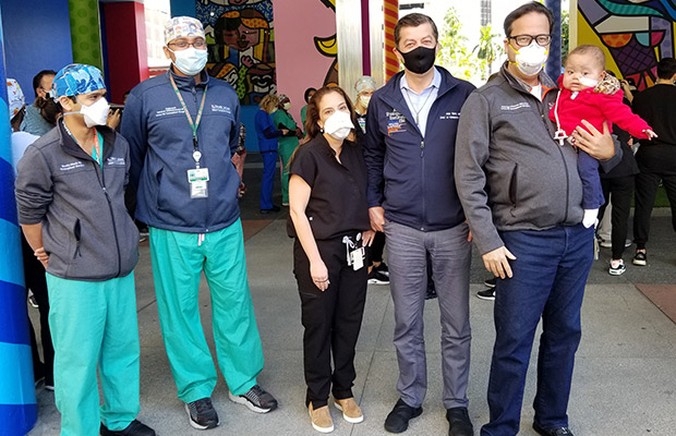 A baby held and surrounded by medical professionals