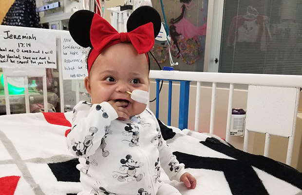 Baby smiling, she is on a hospital bed with a tube coming out of her nose