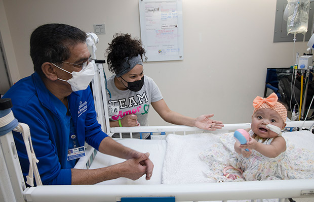 Baby in a hospital bed surrounded by a medical professional and woman