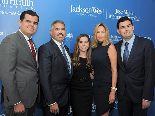 A group of people standing in front of a stand and repeat, there are three men and two women smiling at the camera