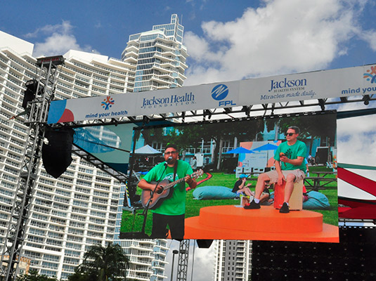 The top of a stage that shows a projection of a man playing guitar