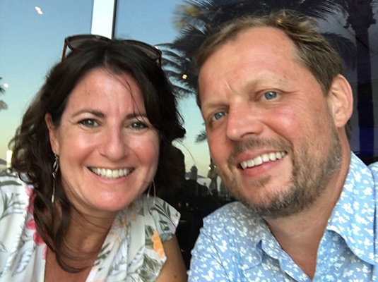 A closeup of a woman and man, they are outdoors and smiling at the camera