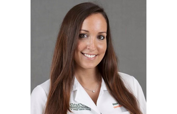 Headshot of a doctor, she has on a white coat, smiles at the camera and has long brown hair