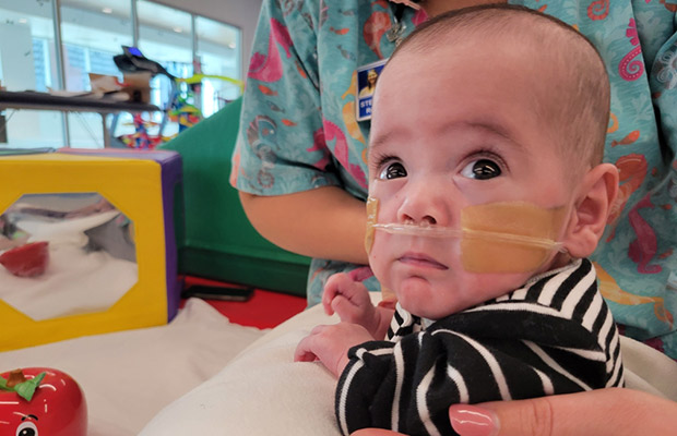 A closeup of a baby on his tummy, he is looking to his right, he has a tube coming out of his nose