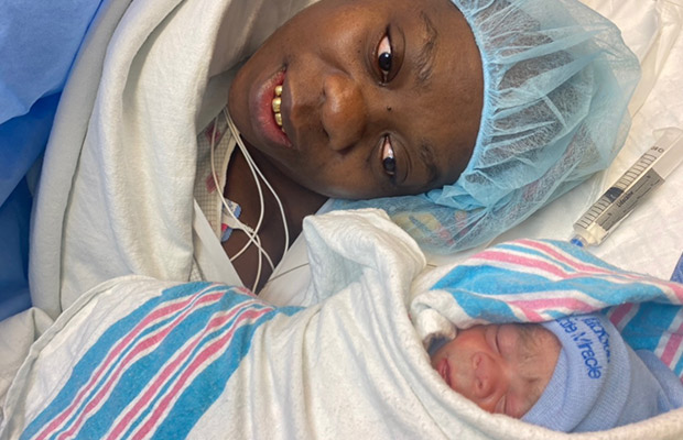 A woman wearing a hospital cap laying next to a baby who is wrapped in a blanket