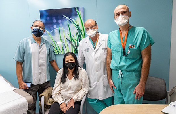 Two people and medical professionals in a medical office, they all look at the camera