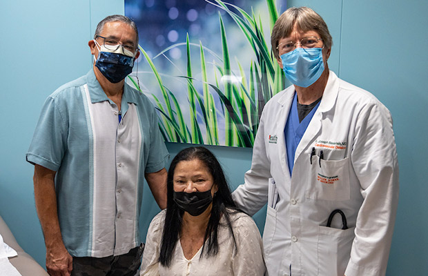 Two people and a medical professional in a medical office, they all look at the camera