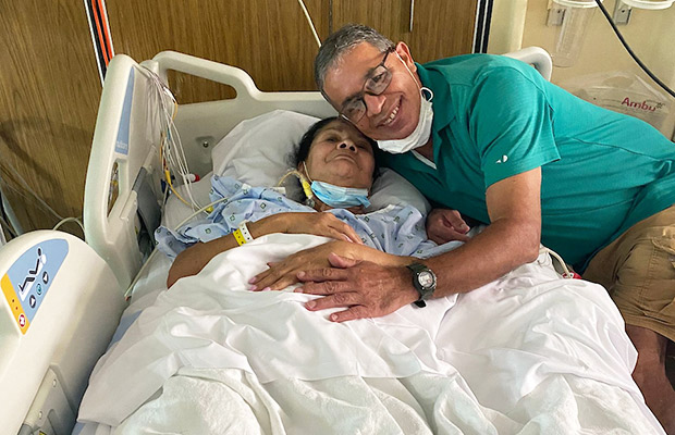 A man hugging a woman who is laying on a medical bed