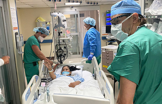 A woman in a medical bed being transported by medical professionals