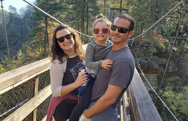 A man, woman, and child outdoors surrounded by nature