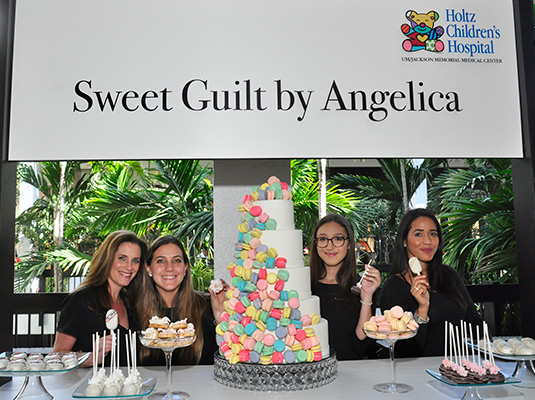 Four women standing behind a booth filled with sweets