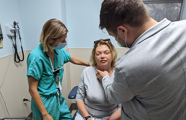 A medical professional checking a patient, they are inside a medical room, there is a men touching the patients neck