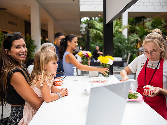 A woman scooping ice cream for a woman and young girl