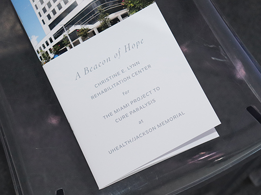 A closeup of an invite that reads A Beacon of Hope, Christine E. Lynn Rehabilitation Center for The Miami Project to Cure Paralysis at UHealth/Jackson Memorial