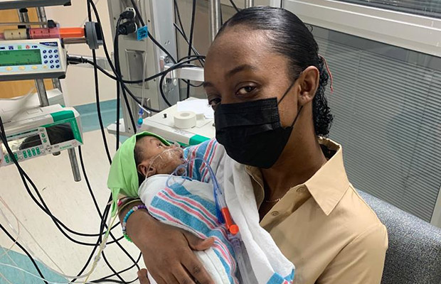 A closeup of a woman holding a baby within a medical room