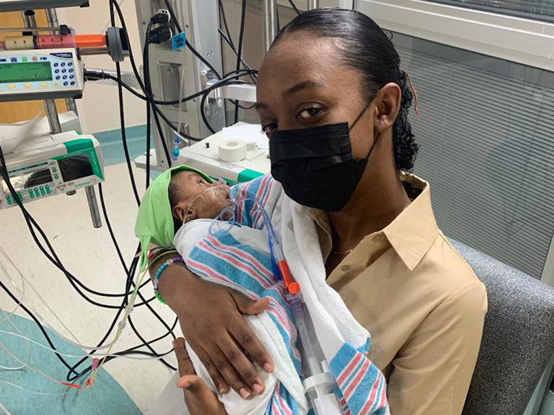 A closeup of a woman holding a baby within a medical room