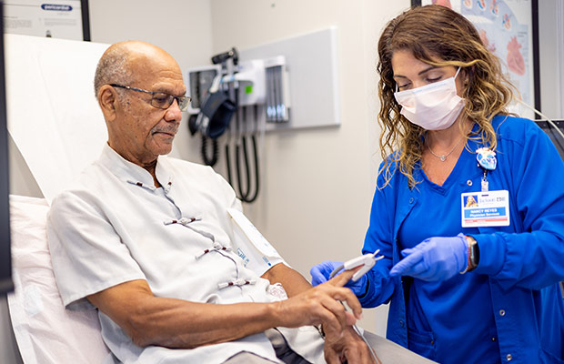 An older male sitting down, a medical professional is taking his vital signs