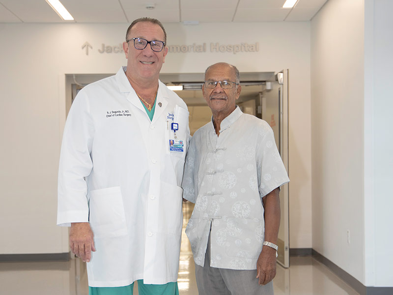 A doctor and patient standing next to each other, they smile at the camera