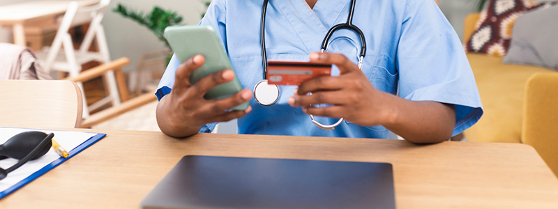Closeup of a nurse using a credit card and her phone