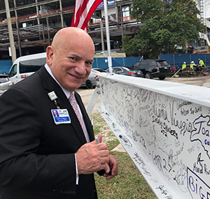 man smiling in front of wall full of signatures