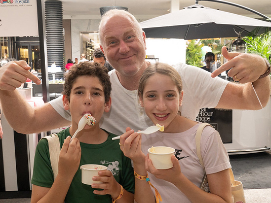 children eating ice cream next to man