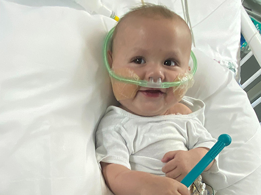 A baby smiling, the baby has tubes coming out of its nostrils