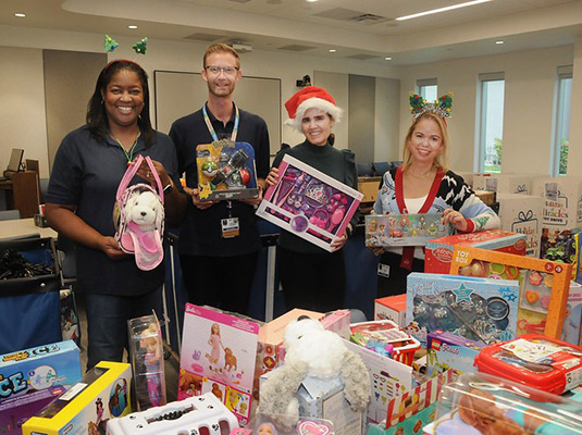 Four adults smiling as they hold up gifts for kids