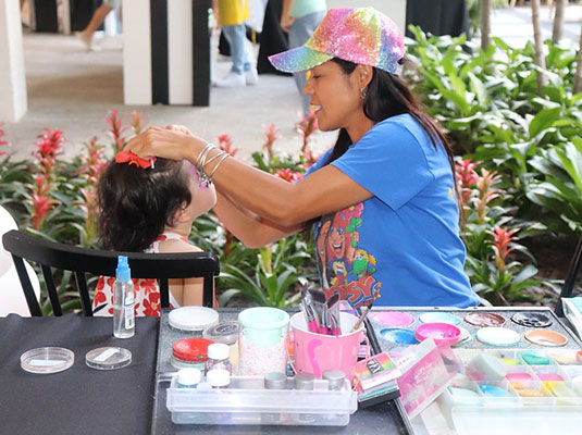 woman doing face painting to little girl