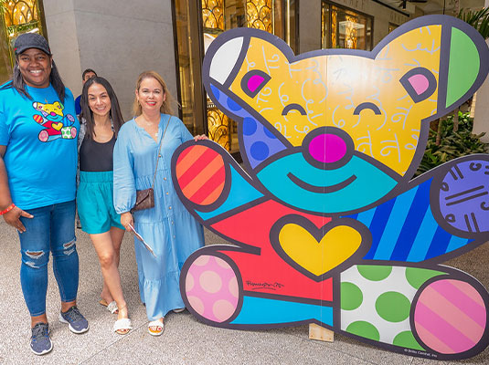 three people posing next to colorful bear