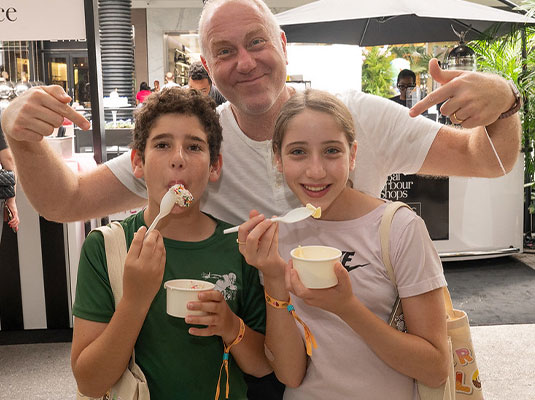 man smiling next to two children eating ice cream