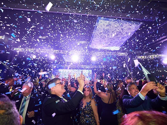 People at a gala celebrating, there's confetti falling from the ceiling