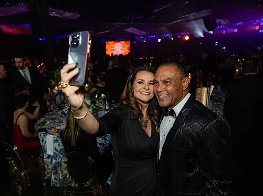 Two people smiling and taking a selfie, they're at a gala