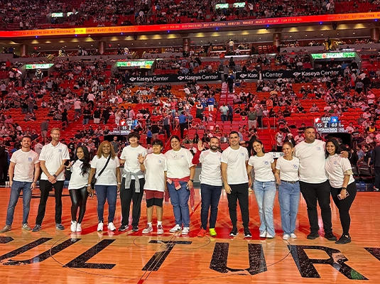 group of people posing in the middle of a professional basketball court