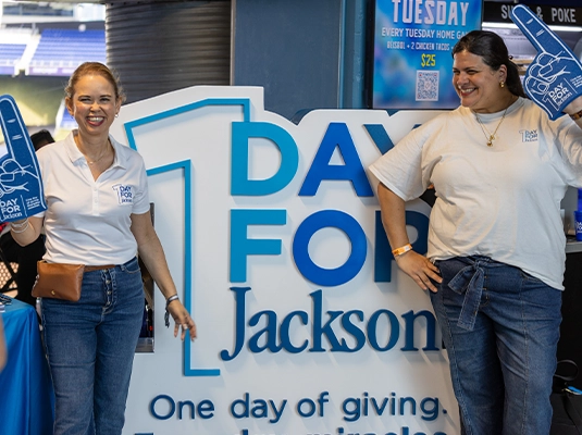 two women posing next to the One Day for Jackson logo