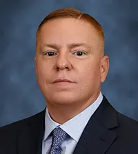 Closeup of man looking at the camera, he has on a suit and tie