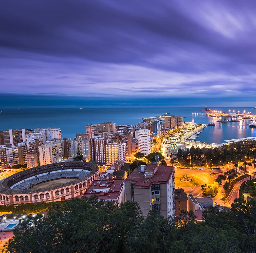 An aerial view of Malaga cityscape at night with views to the ocean and buildings