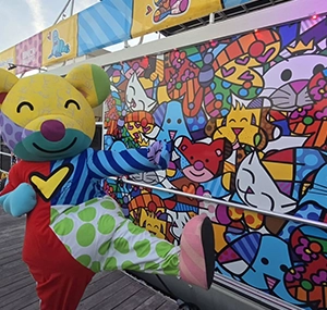 person dressed as a colorful bear next to a mural